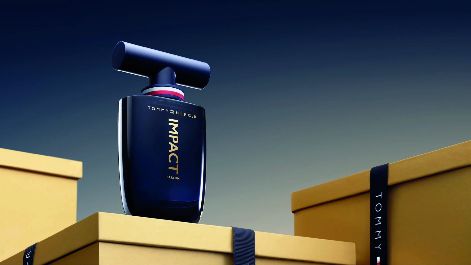 Presentación completa del perfume Tommy Hilfiger Impact Parfum 100ml mostrando frasco y caja sobre superficie iluminada