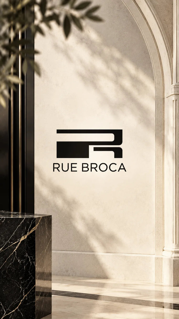 Colección de perfumes Rue Broca originales en Colombia, con el logotipo de la marca centrado sobre un elegante escenario parisino en tonos crema, negro y dorado.