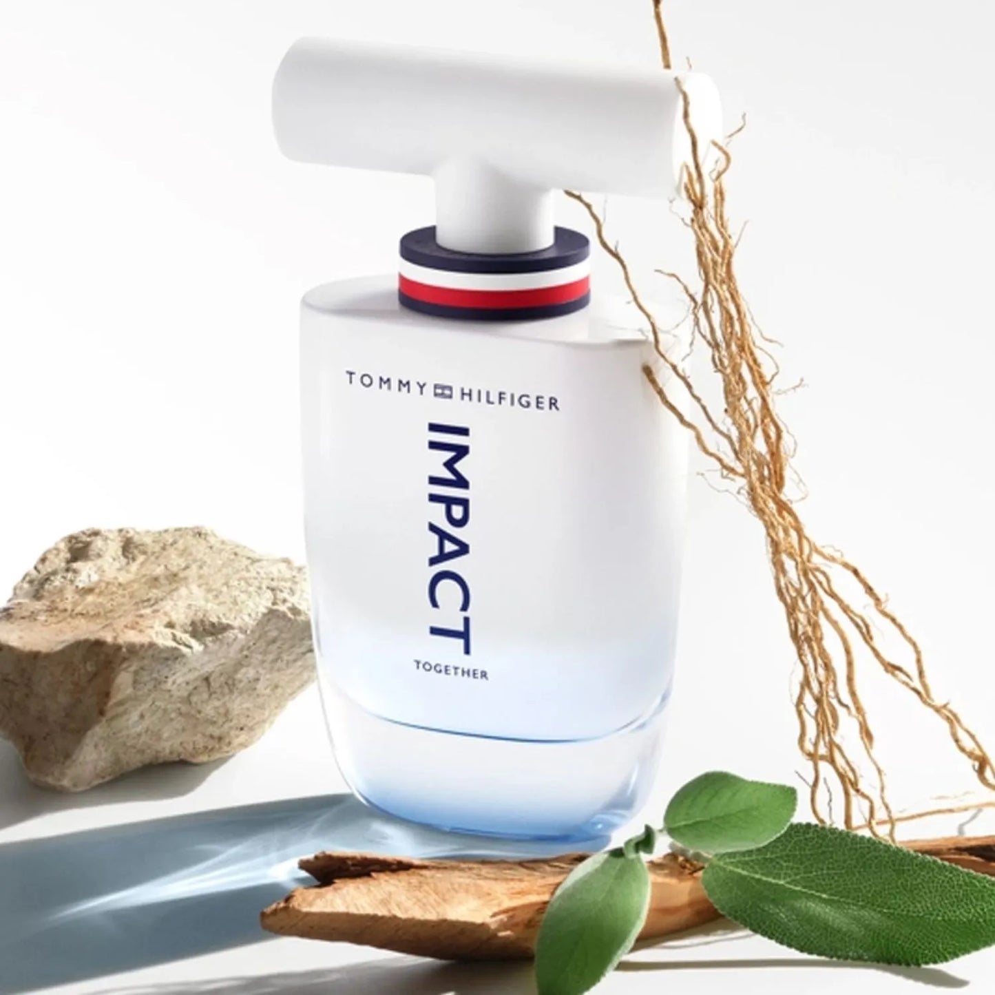 perfume Tommy Hilfiger Impact Together con su frasco transparente y azul colocado sobre la caja de la fragancia